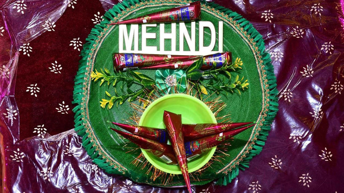 Colourful decorated mehndi plate with natural henna cones and greenery