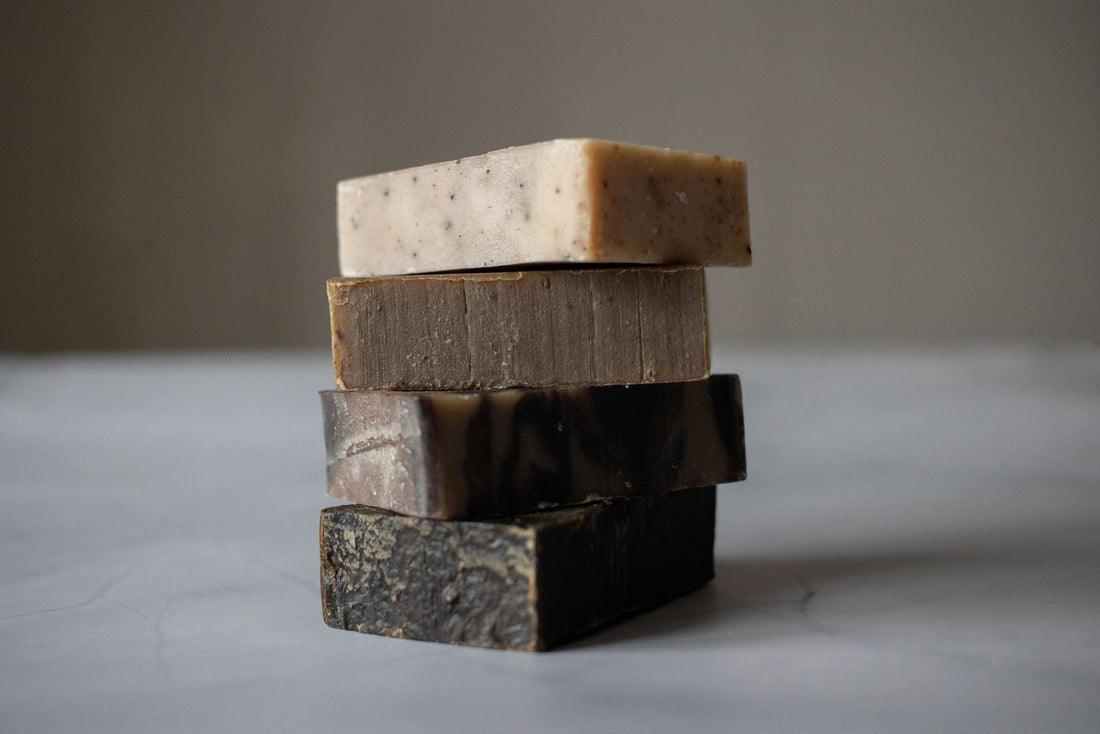 Stack of four handmade herbal soap bars in natural earth tones