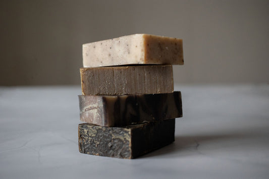Stack of four handmade herbal soap bars in natural earth tones